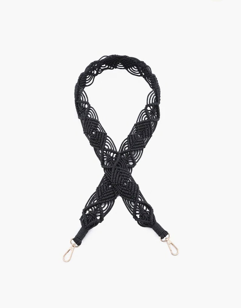 May include: Black woven strap with silver clasps. The strap is made of a thick, braided cord and has a decorative pattern.