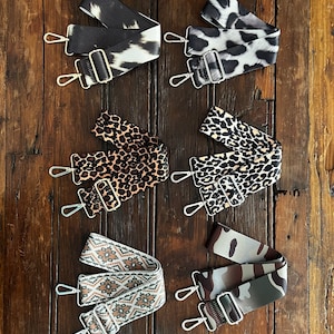 May include: Six different patterned fabric straps with silver hardware. The straps are in a variety of animal prints, including leopard, zebra, and camouflage.