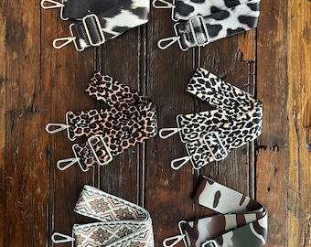May include: Six different patterned fabric straps with silver hardware. The straps are in a variety of animal prints, including leopard, zebra, and camouflage.