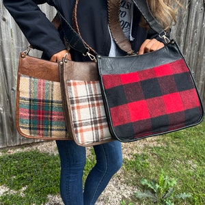 May include: Three brown leather shoulder bags with plaid fabric accents. The bags have a black leather strap and a flap closure. The plaid patterns include red, green, and white.
