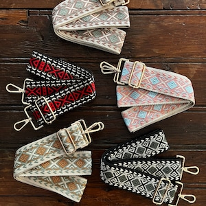 May include: Five different patterned fabric straps with gold metal clasps. The straps are all white with different colored geometric patterns.