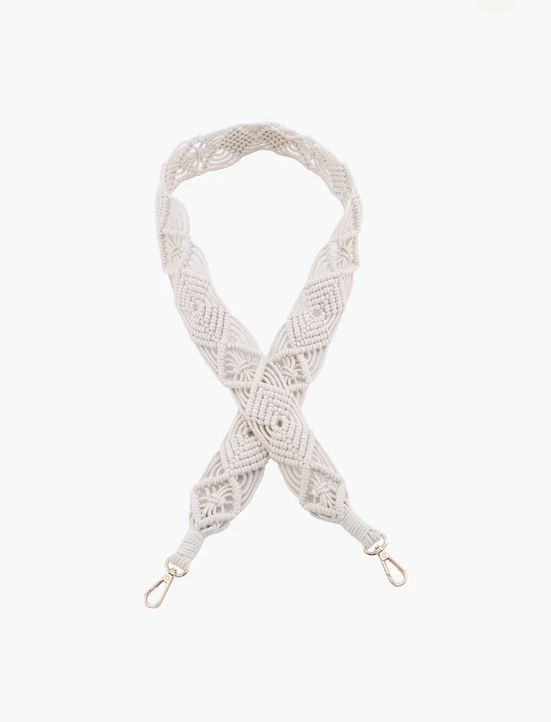 May include: White macrame bag strap with silver clasps. The strap is made of a thick, woven cord and has a diamond pattern.