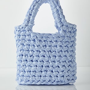 May include: A light blue crocheted tote bag with a braided handle.