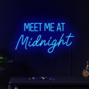 May include: Neon sign with blue light that reads "Meet Me At Midnight".