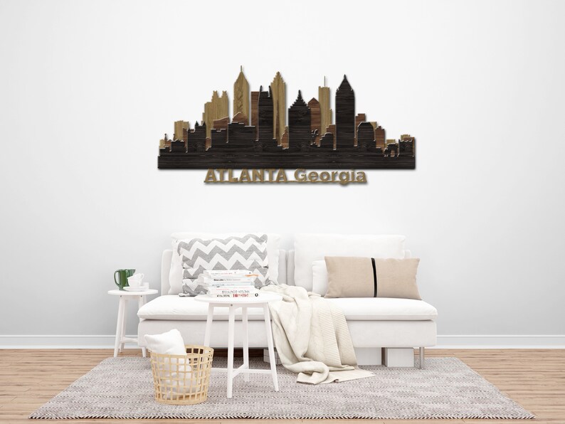 May include: Wooden wall art of the Atlanta, Georgia skyline. The artwork shows a silhouette of the city's buildings in shades of brown and black. The city name is displayed in gold lettering below the skyline.