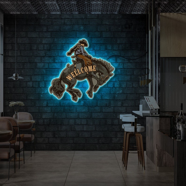 Op de afbeelding: Neon-bord met een cowboy die een wild paard berijdt. Het bord zegt "WELCOME" in een vintage lettertype.