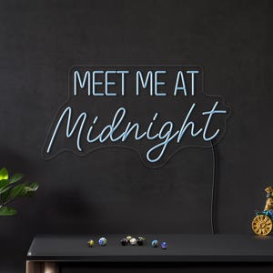 May include: Blue neon sign with the text "Meet Me At Midnight" on a black background.