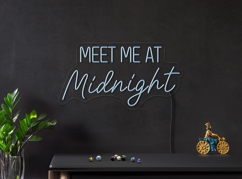 May include: Blue neon sign with the text "Meet Me At Midnight" on a black background.