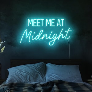 May include: A teal blue neon sign with the text "Meet Me At Midnight" on a black wall above a bed with blue and white bedding.
