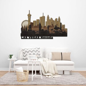 May include: Wooden wall art depicting the Las Vegas skyline with the text "Las Vegas Nevada" at the bottom. The skyline is made of different shades of brown wood and features iconic landmarks like the Eiffel Tower, the Stratosphere Tower, and the High Roller observation wheel.