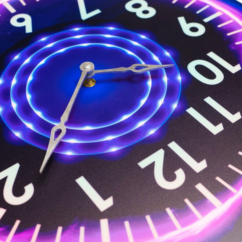 May include: A close-up of a clock face with glowing purple and blue lights around the center. The clock hands are silver and point to the numbers 12 and 2. The numbers on the clock face are white and outlined in black.
