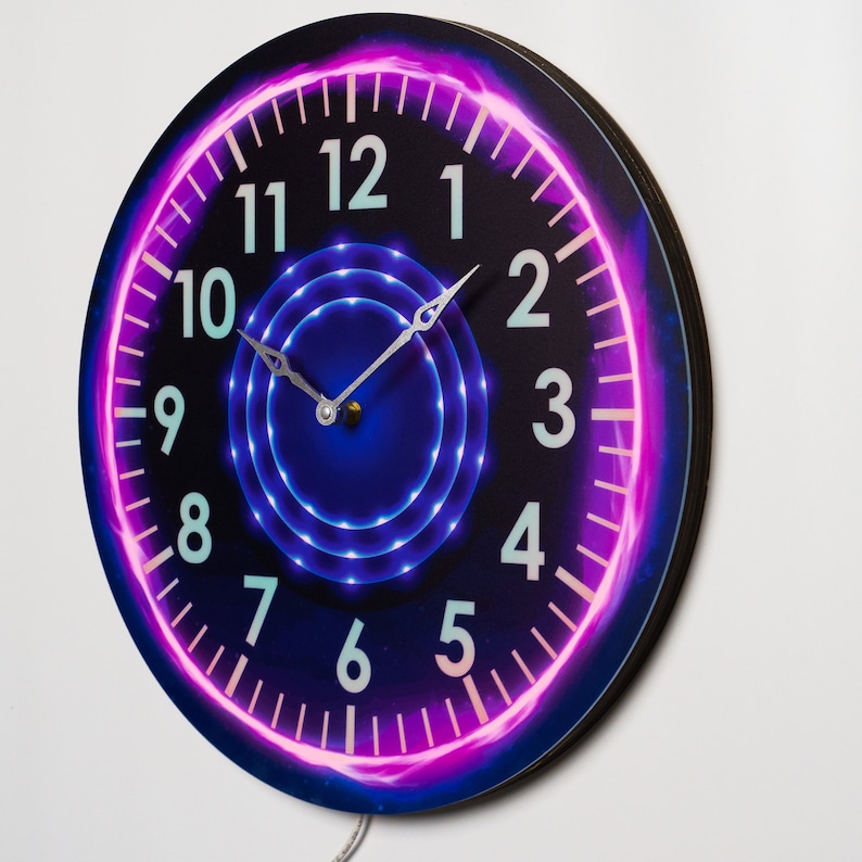 May include: A round clock with a black background and a pink and purple neon glow around the numbers. The numbers are white and the clock hands are silver.