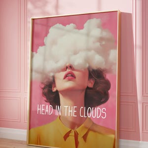 May include: A pink and white art print featuring a woman's face with a cloud covering her eyes. The text "HEAD IN THE CLOUDS" is written below the woman's face.