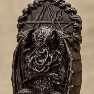 May include: A dark brown, detailed, sculpted figurine of Cthulhu, the fictional cosmic entity, sitting on a throne with a pentagram behind him.