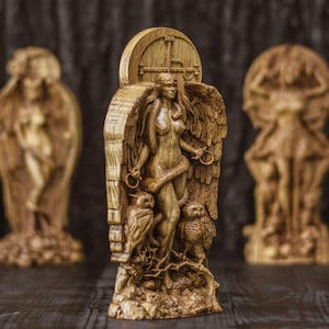 May include: A wooden sculpture of a female figure with wings, standing on a base with two owls. The figure is carved in a detailed style and has a natural wood finish.