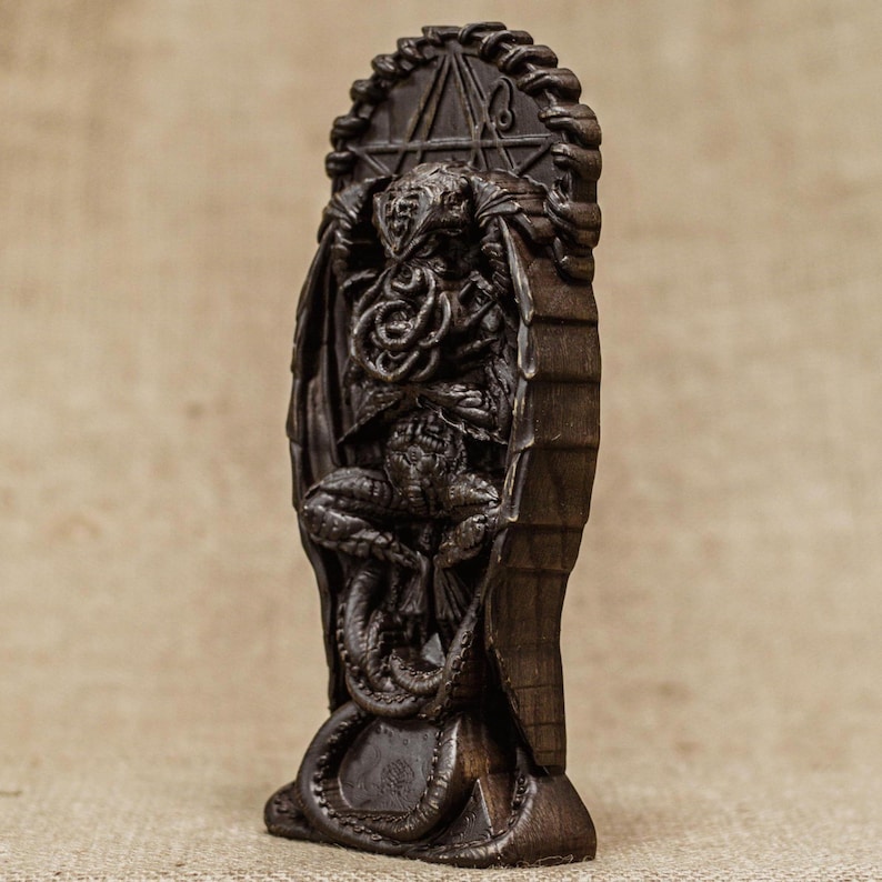 May include: A dark brown wooden sculpture of Cthulhu, a fictional cosmic entity from the works of H.P. Lovecraft. The sculpture depicts Cthulhu with tentacles and wings, and is set against a background of a pentagram.