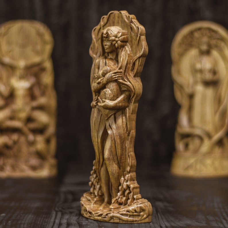 Puede incluir: Una escultura de madera de una mujer de pie en un &aacute;rbol, sosteniendo un animal peque&ntilde;o en sus brazos. La escultura est&aacute; tallada en un estilo detallado y tiene un acabado de madera natural.