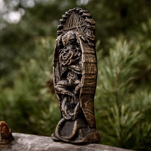 May include: A wooden carving of a creature with tentacles, resembling a Cthulhu mythos monster. The carving is detailed and intricate, with a dark brown finish. The creature is depicted sitting on a throne, with a symbol carved above it.