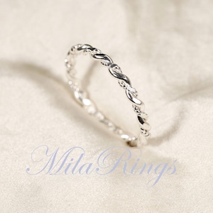 Peut inclure: Une bague argent&eacute;e avec un motif torsad&eacute;. La bague est pr&eacute;sent&eacute;e sur un fond blanc. Le texte "Mila Rings" est visible dans l'image.