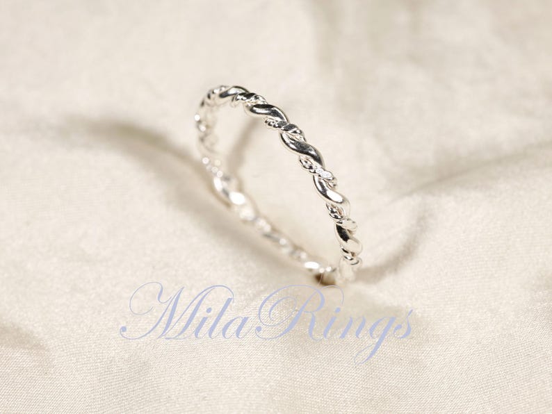 Peut inclure: Une bague argent&eacute;e avec un motif torsad&eacute;. La bague est pr&eacute;sent&eacute;e sur un fond blanc. Le texte "Mila Rings" est visible dans l'image.