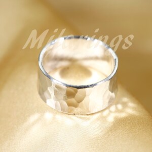 Op de afbeelding: Een zilveren gehammerde bandring. De ring is breed en heeft een getextureerd oppervlak.