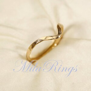 May include: A gold, wavy, hammered ring. The ring is simple and elegant.