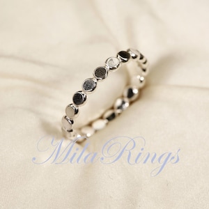 May include: A silver ring with a circle design. The ring is made of small, round beads that are connected together.