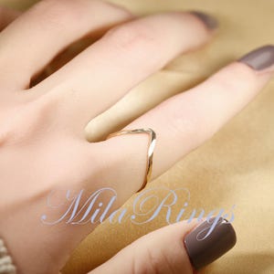 May include: A gold-toned, V-shaped ring worn on a finger. The ring is simple and delicate.