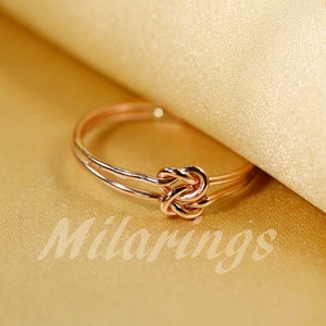 May include: A rose gold knot ring with a double band.