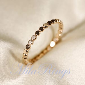 Peut inclure: Une délicate bague en or avec un design perlé. La bague est composée de petites perles rondes qui sont uniformément espacées le long de la bande.