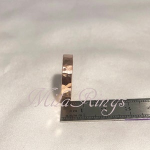 May include: A close-up of a hammered gold ring, measured against a ruler. The ring is approximately 1.5 cm wide.