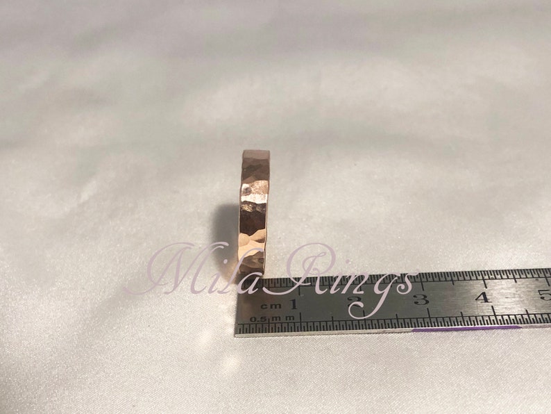 May include: A close-up of a hammered gold ring, measured against a ruler. The ring is approximately 1.5 cm wide.