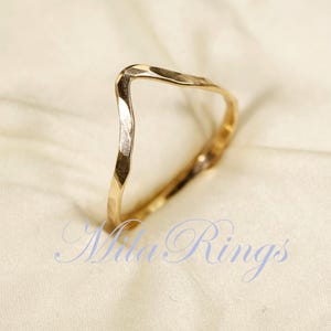 May include: A gold hammered ring with a V-shaped design. The ring is simple and elegant, and would make a great gift for a special occasion.