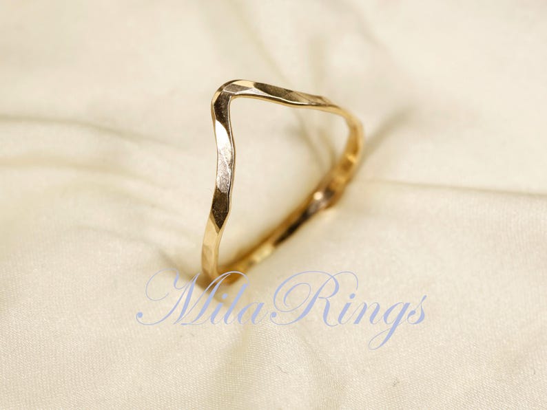 May include: A gold hammered ring with a V-shaped design. The ring is simple and elegant, and would make a great gift for a special occasion.