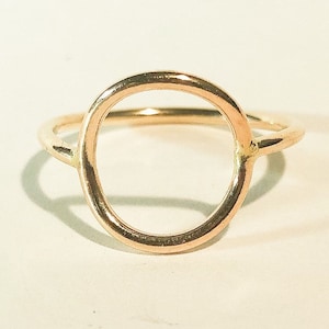 May include: A gold circle ring with a simple, minimalist design.
