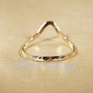 May include: A gold-toned ring with a hammered finish and a V-shaped opening.