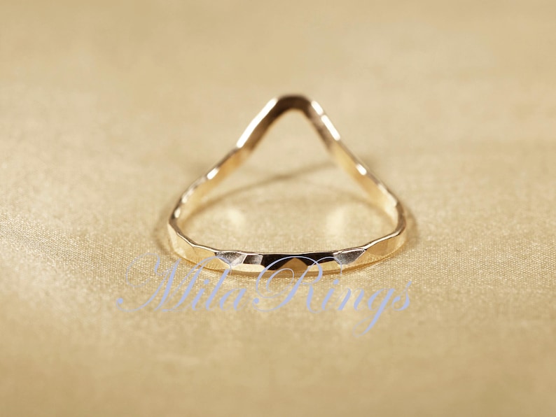 May include: A gold-toned ring with a hammered finish and a V-shaped opening.