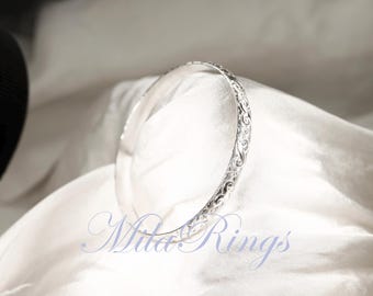 May include: A silver bangle bracelet with an intricate floral design.