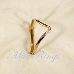 May include: A gold hammered ring with a unique, wavy design. The ring is simple and elegant, perfect for everyday wear.