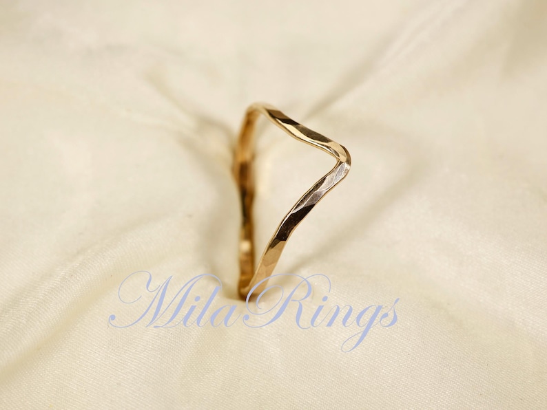 May include: A gold hammered ring with a unique, wavy design. The ring is simple and elegant, perfect for everyday wear.