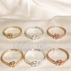 Op de afbeelding: Zes gouden, zilveren en ros&eacute;gouden ringen met een knoopdesign. De ringen zijn allemaal in dezelfde stijl, maar in verschillende kleuren.