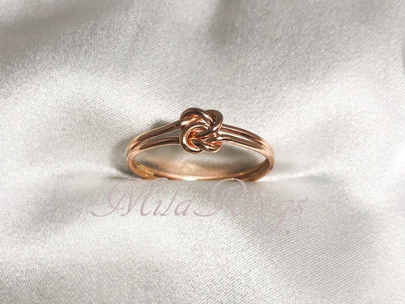 Op de afbeelding: Een knoop ring van ros&eacute;goud met een eenvoudig ontwerp. De ring is gemaakt van twee banden metaal die samen gedraaid zijn om een knoop te vormen.