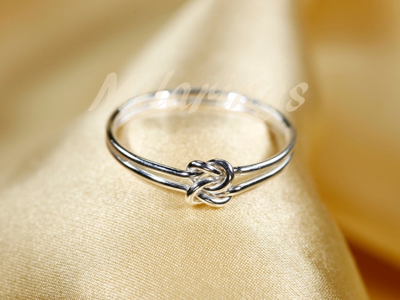 May include: A silver ring with a knot design. The ring is simple and elegant.