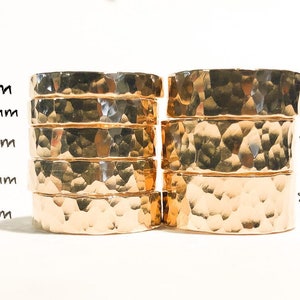 K&ouml;nnte beinhalten: Ein Satz von acht goldfarbenen, geh&auml;mmerten Metallringen, die in zwei Spalten gestapelt sind. Die Ringe sind mit ihrer Breite in Millimetern beschriftet: 3 mm, 3,5 mm, 4 mm, 4,5 mm, 5 mm, 6 mm, 7 mm und 8 mm.