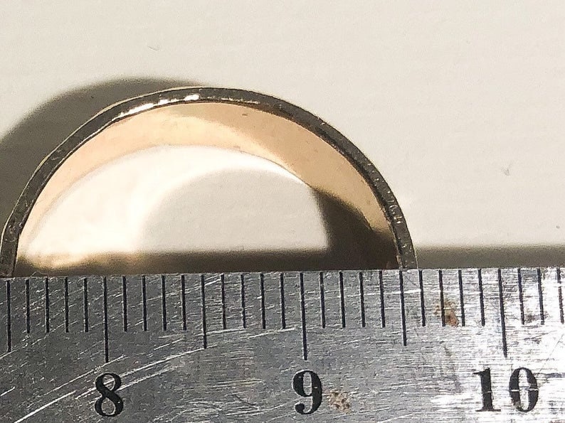 May include: A gold-colored ring is measured with a ruler. The ring is between 8 and 9 inches in diameter.