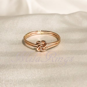 May include: A rose gold ring with a double band and a knot design.