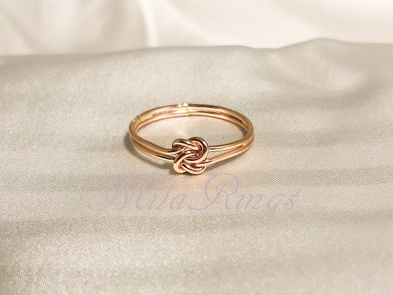 Op de afbeelding: Een ring van ros&eacute;goud met een dubbele band en een knoopdesign.