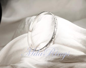 May include: A silver bangle bracelet with an intricate floral design.