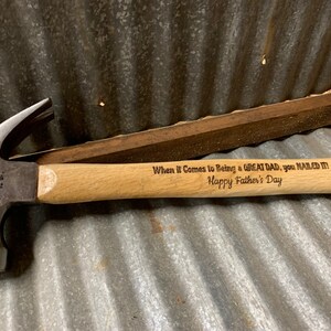 May include: A wooden-handled hammer with a metal head. The handle is engraved with the text "When it Comes to Being a GREAT DAD, you NAILED IT! Happy Father's Day."