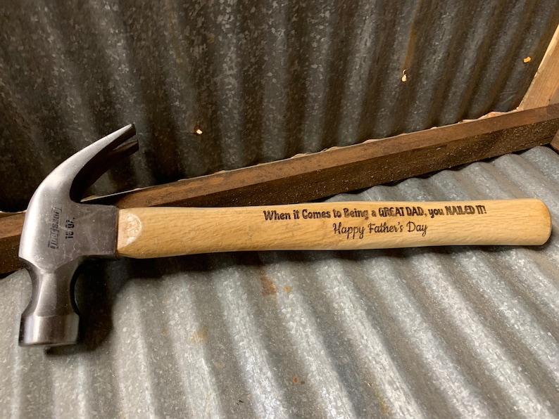 May include: A wooden-handled hammer with a metal head. The handle is engraved with the text "When it Comes to Being a GREAT DAD, you NAILED IT! Happy Father's Day."